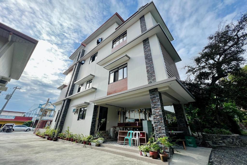 MC's L Transient House في Bantay: مبنى ابيض امامه بعض النباتات
