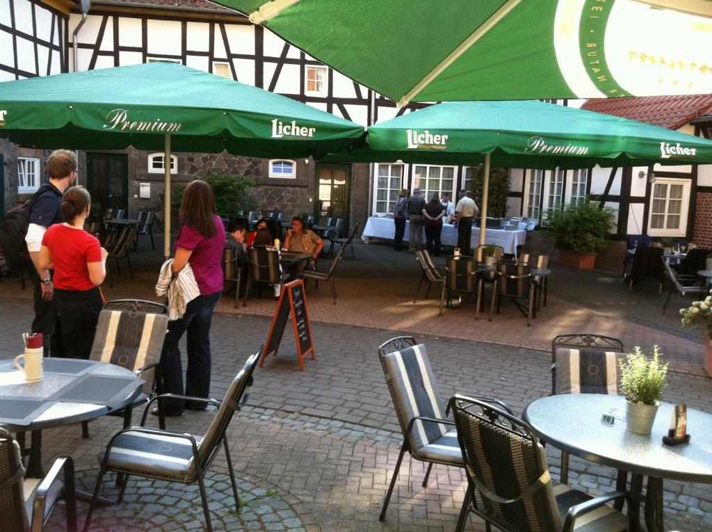 a group of people standing in a patio with tables and umbrellas at Hotel Mühlenhof Lollar in Lollar