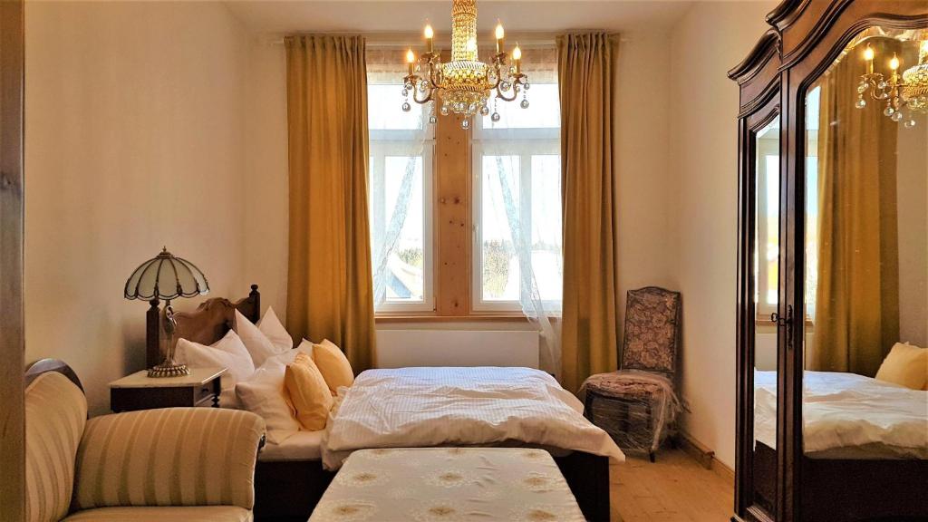 una camera con due letti, un lampadario a braccio e una finestra di Superior-Komfort-Suite-90m2-bis-5-Personen-im-Jugendstil-Gruenderzeit-Villa-im-Harz a Sankt Andreasberg