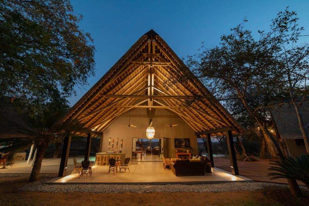 a large building with a triangle roof with tables and chairs at Tomo Safari Lodge in Hoedspruit