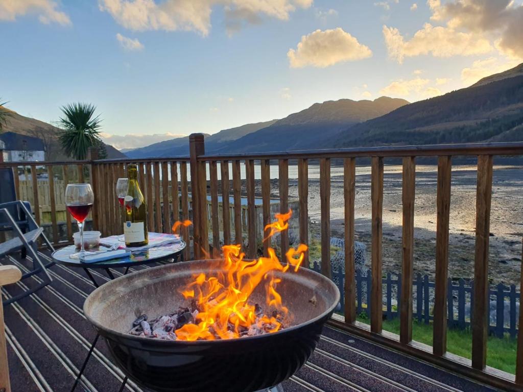 a fire pit on a deck with a view of the water at Cottage on the Loch in Arrochar