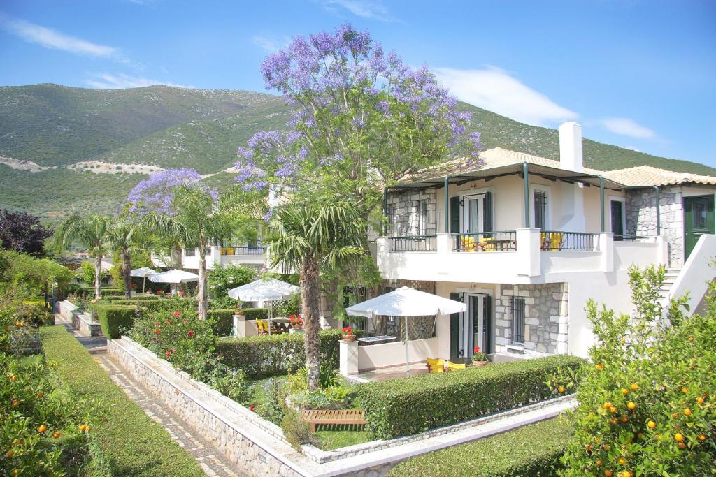 a large white house with a garden in front of it at Sunny Garden Aparthotel in Ancient Epidauros