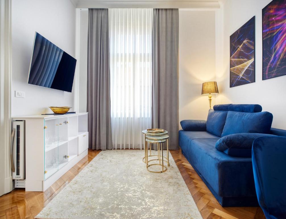 ein Wohnzimmer mit einem blauen Sofa und einem TV in der Unterkunft Art Borelli Vranski Apartment by Irundo in Zagreb