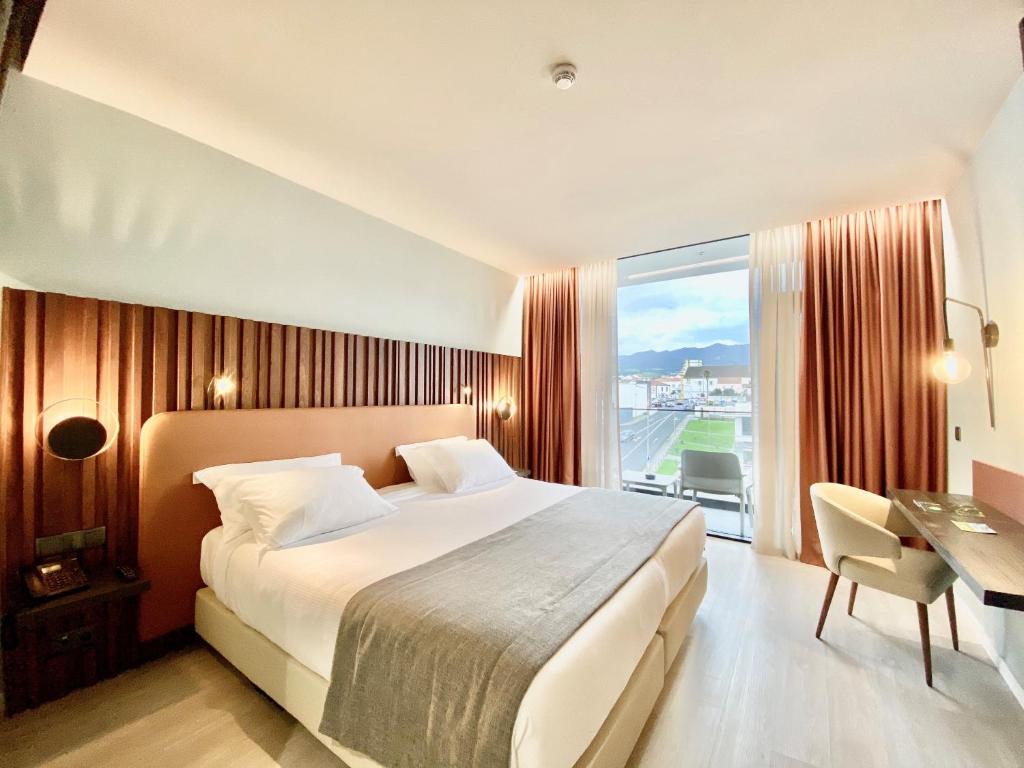 a hotel room with a large bed and a window at Hotel Verde Mar & SPA in Ribeira Grande
