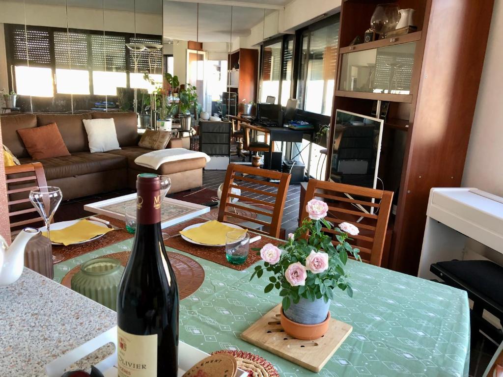 - une bouteille de vin et des fleurs sur une table dans le salon dans l'établissement Nid de rêve, vue imprenable sur Paris et terrasse 10m2, à Paris