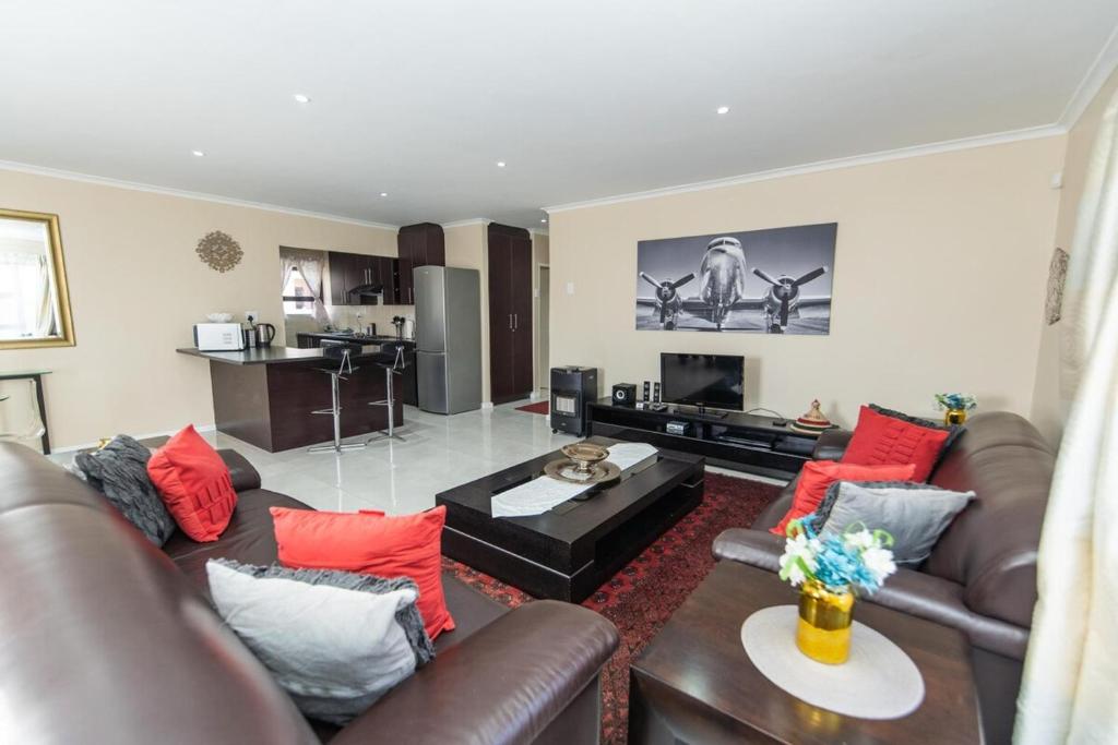 a living room with brown leather furniture and red pillows at Cosy Home In Bluewater Bay in Amsterdamhoek