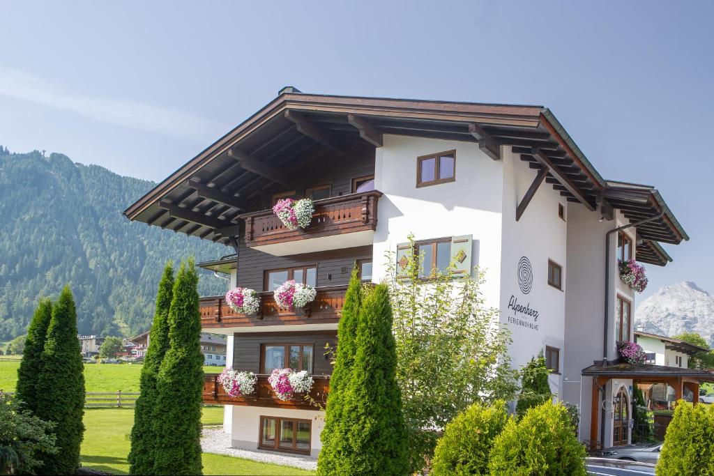 a building with flowers on the balconies and trees at Alpenherz Ferienwohnungen in Pertisau