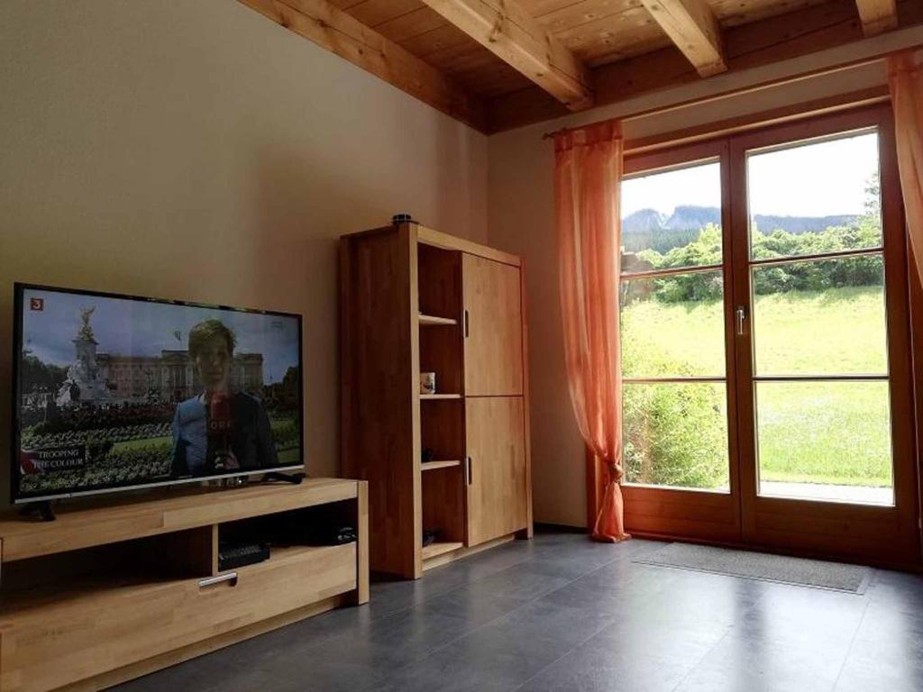 a living room with a television and a large window at Feriendorf Reichenbach - Biberweg 12 in Nesselwang