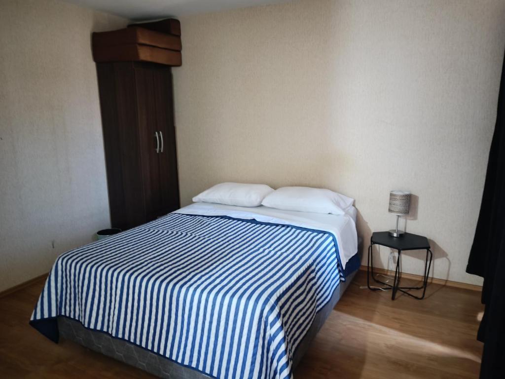1 dormitorio con 1 cama con manta de rayas azul y blanco en Apartamento en chiclayo Perú, en Chiclayo