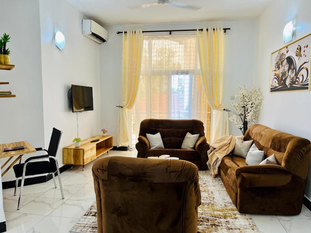 sala de estar con 2 sofás y TV en Lomes cozy home, en Dar es Salaam