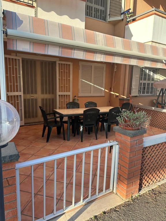 eine Terrasse mit einem Tisch, Stühlen und einem Zaun in der Unterkunft Casa vacanza Ylenia in Mascali