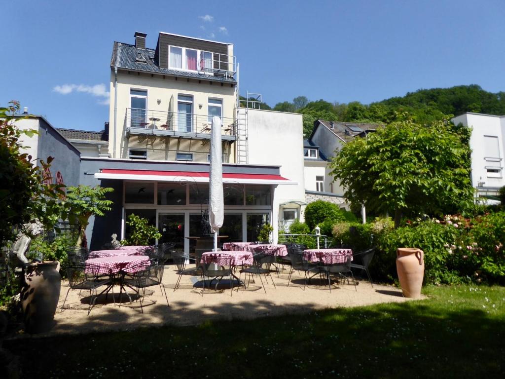 un patio con mesas rosas y sillas frente a un edificio en Hotel Weinhaus Hoff, en Bad Honnef am Rhein