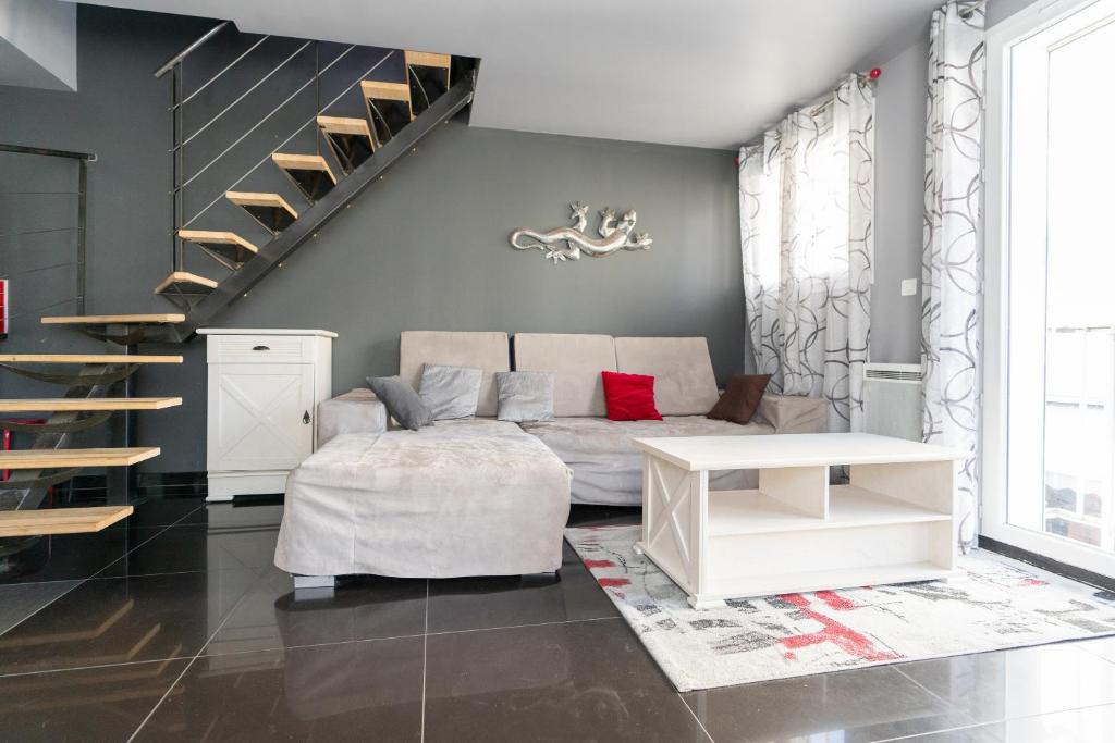 a living room with a couch and a staircase at appartement de la barque bleue in Le Grau-du-Roi