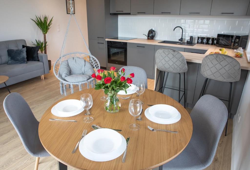 a dining room table with plates and flowers on it at Luxus Apartament Bella in Gdynia