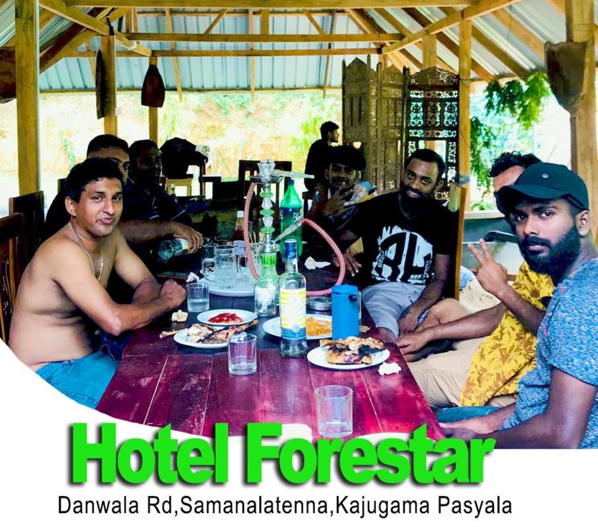 a group of men sitting around a table with food at Forestar Villa and Restaurant in Nittambuwa