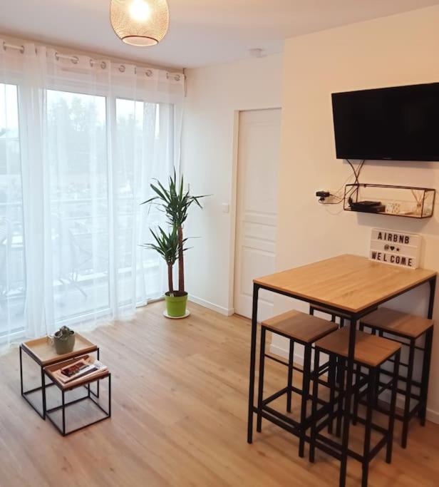 un salon avec une table et une télévision dans l'établissement Bel appartement proche gare et centre-ville, à Rambouillet