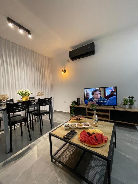 a living room with a table and a tv at דירת אירוח מפנקת בעיר אשקלון - 5 דקות נסיעה מהים in Ashkelon