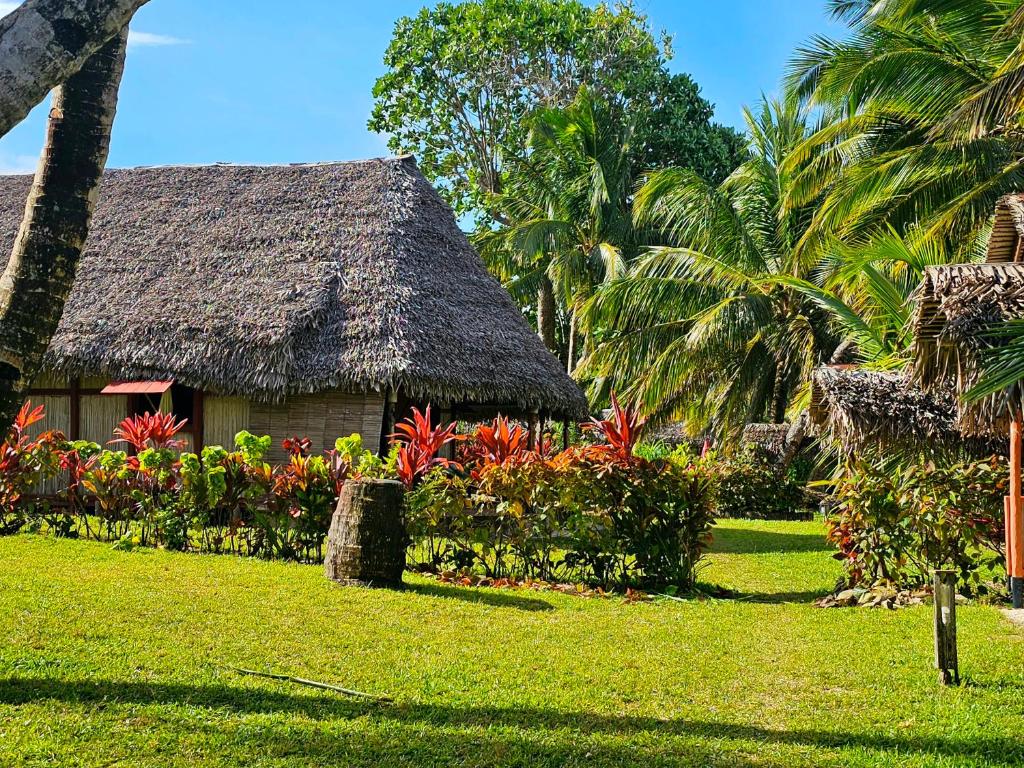 une maison au toit de chaume et une cour fleurie dans l'établissement KINTANA LODGE, sur l'île aux Nattes