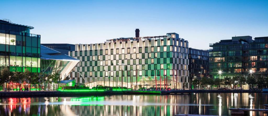 un grand bâtiment en verre à côté d'une rivière avec des bâtiments dans l'établissement Anantara The Marker Dublin- A Leading Hotel of the World, à Dublin