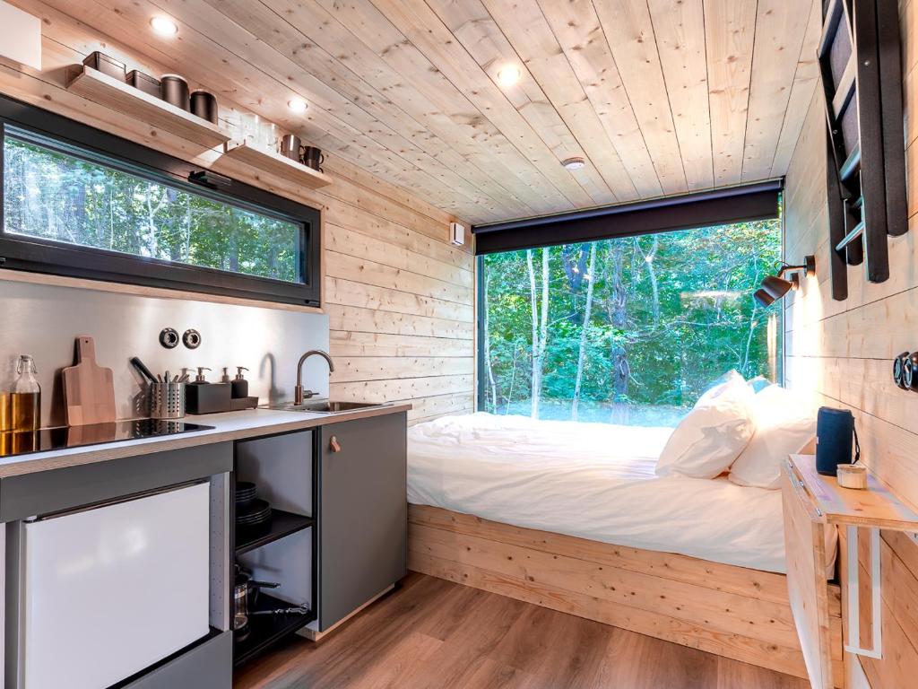 1 dormitorio en una casa pequeña con cama y ventana en Chic Sauna Cabin Near the Sea - VULIN Cabin Nº01, 