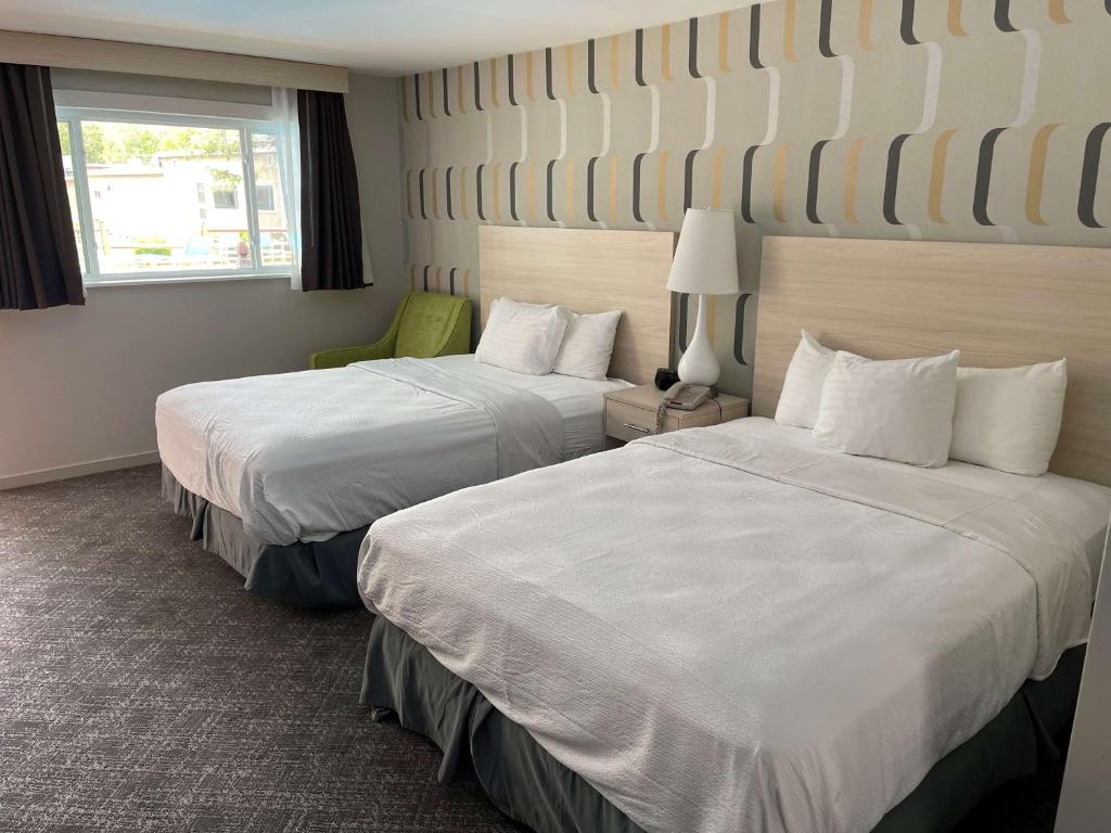 a hotel room with two beds and a green chair at Woodwards White Mountain Resort, BW Signature Collection in Lincoln