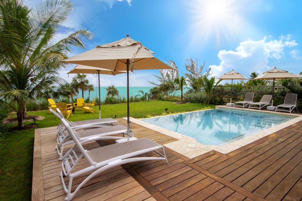 - une terrasse avec des chaises et un parasol à côté de la piscine dans l'établissement Wild Orchid home, à Governorʼs Harbour