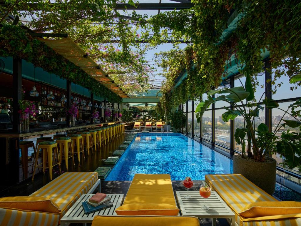 a swimming pool with yellow chairs and a bar at The Smallville Hotel in Beirut