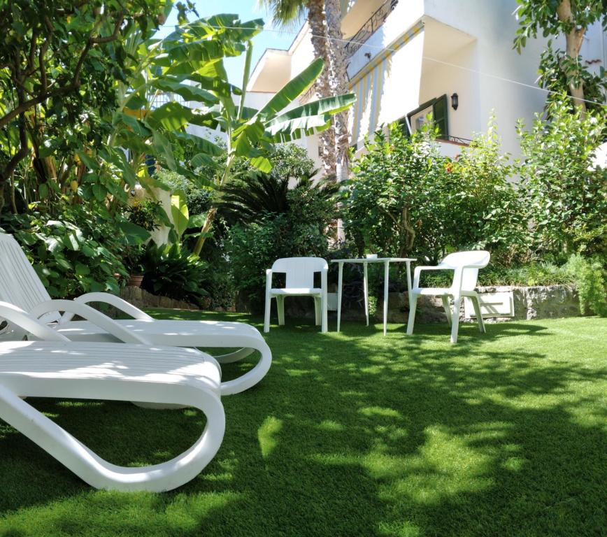 a group of white chairs and tables in a yard at Hotel Villa Angelica in Ischia