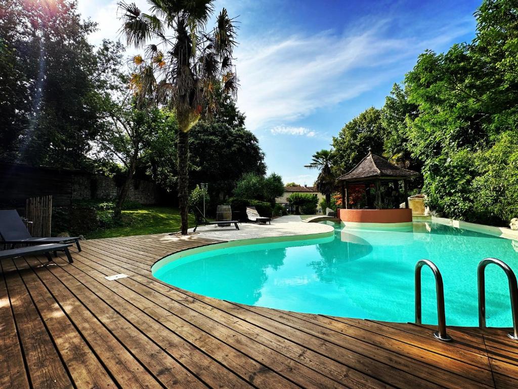 a swimming pool with a wooden deck and a gazebo at Gite l’Oasis in Astaffort