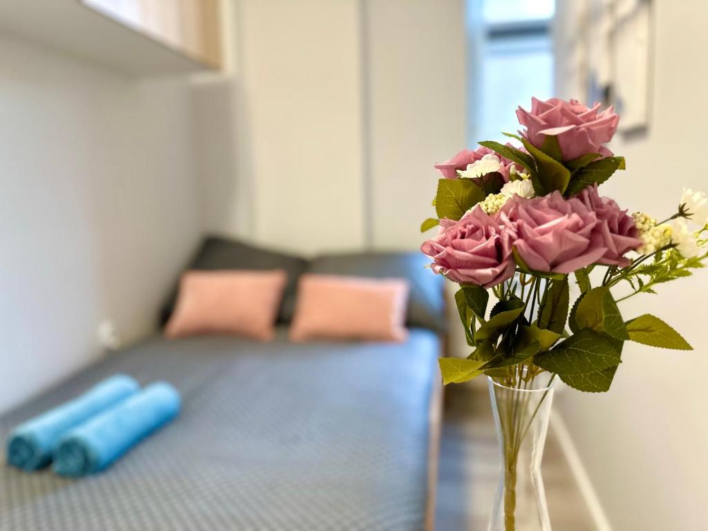 un jarrón lleno de rosas rosas sentadas en una mesa en MMRent Mountain Room en Gdansk