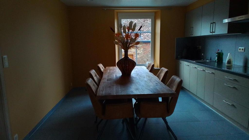 une table à manger avec des chaises et un vase avec des fleurs. dans l'établissement La Ferme Villa 2, à Bastogne