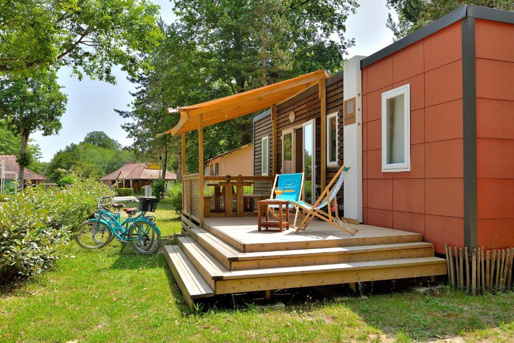 孔布勒的住宿－Camping Etang de la Vallée，一个小房子,有门廊和一辆蓝色的自行车