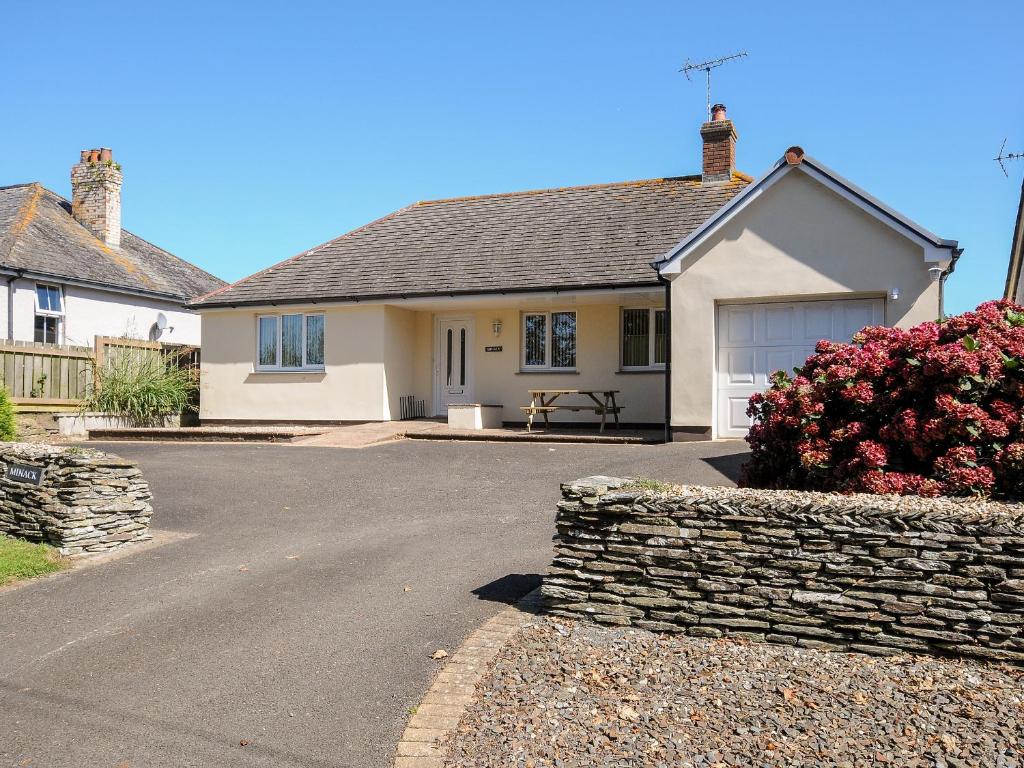 uma casa com uma parede de pedra e uma entrada em Minack em Bude