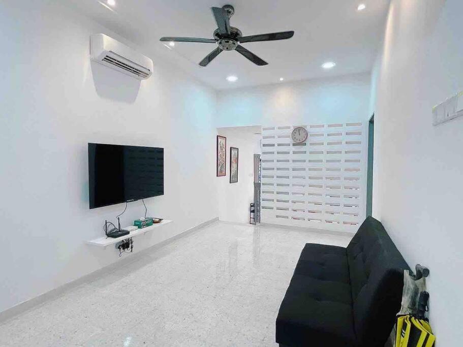 a living room with a black couch and a flat screen tv at Cheerful 27 Home with BBQ grill in Cheras