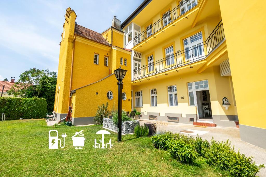 um grande edifício amarelo com um relvado em frente em Albizia-Apartments em Baden