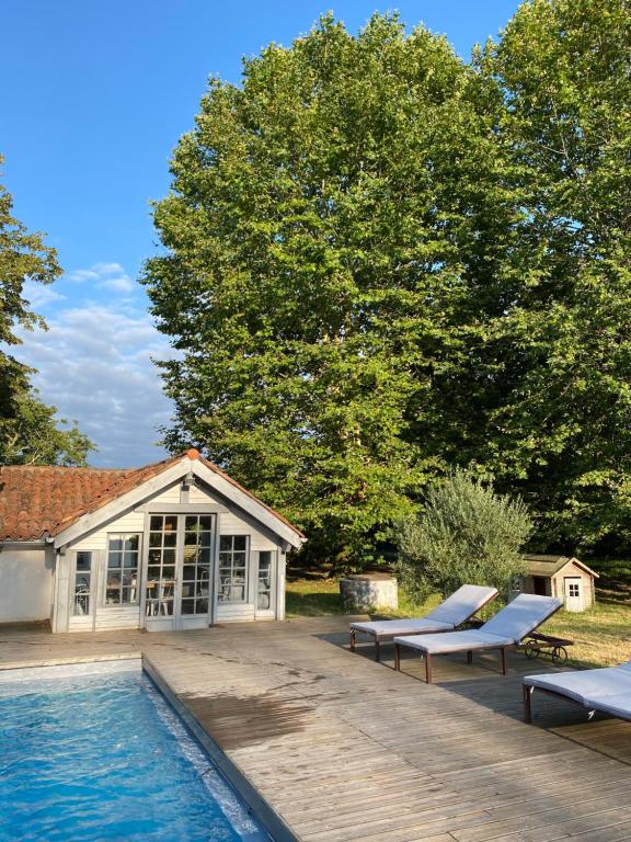 una piscina con 2 tumbonas junto a una casa en Domaine Au Bon, en Angresse