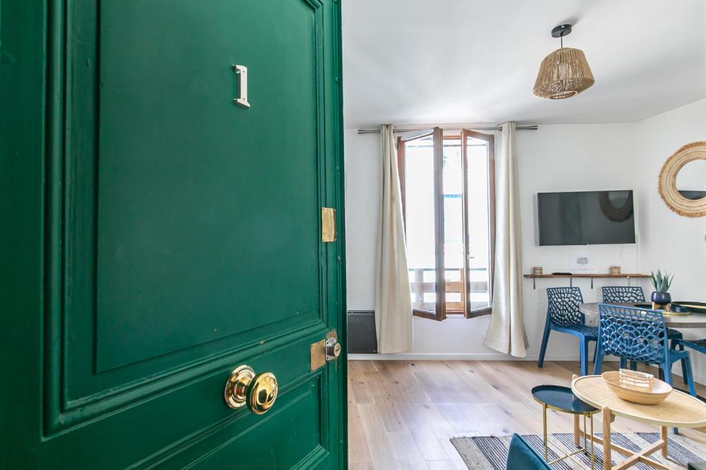 eine grüne Tür in einem Zimmer mit einem Tisch und Stühlen in der Unterkunft MBA Splendide Appart - Diderot 1 - Proche de Nation in Montreuil