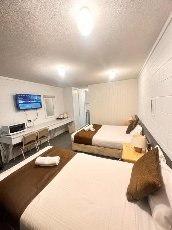 a hotel room with two beds and a desk at Bendigo Motor Inn in Bendigo