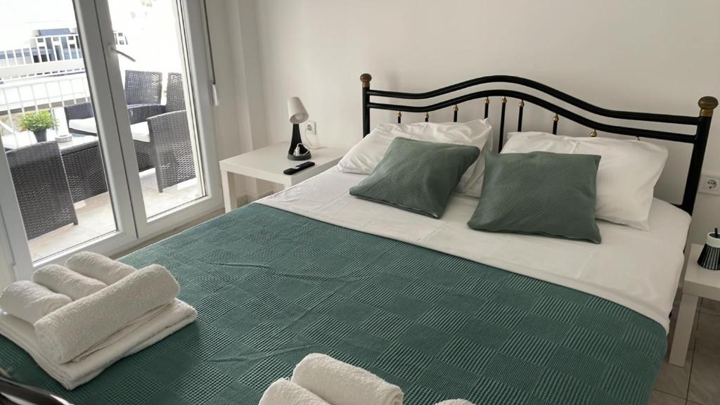 a bedroom with a large bed with green sheets and pillows at Sunny Peraia Apartment in Perea