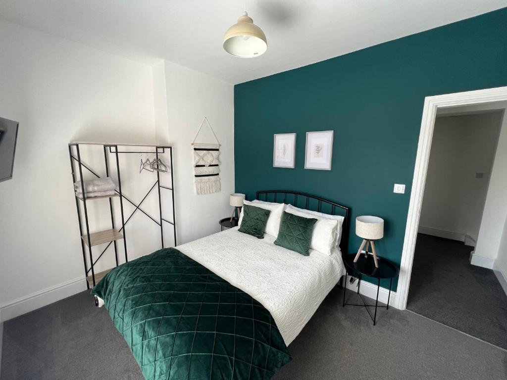 a bedroom with a bed and a blue wall at Cleethorpes - New 2 Bedroom house close to beach in Cleethorpes