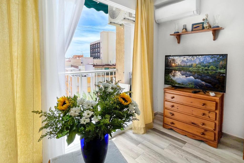 a vase with flowers in a room with a window at Azul Cómodo, bonito y céntrico in Calpe