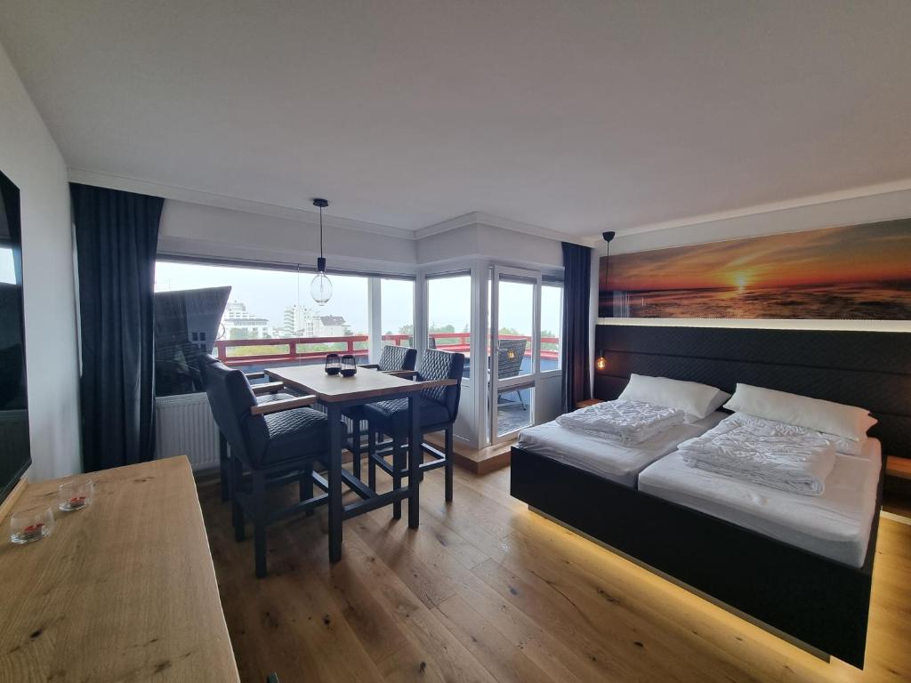 a bedroom with a bed and a table and a dining room at LITTLE SKYSUITE Terrassenhaus W 94 in Cuxhaven