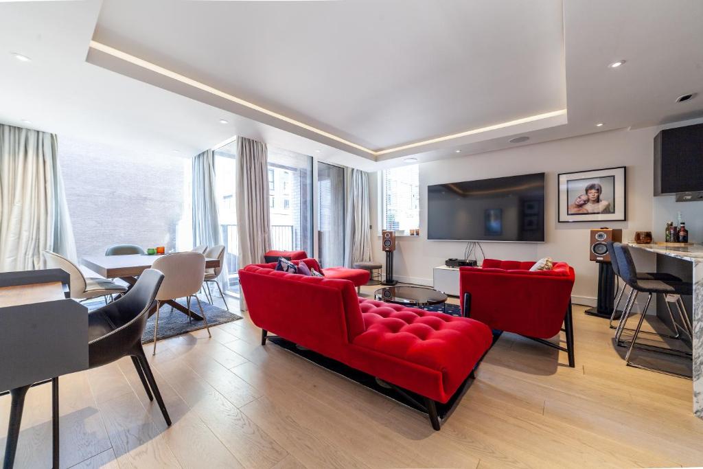 a living room with red couches and a dining room at Stylish 2-BR ground floor apt in Chelsea in London