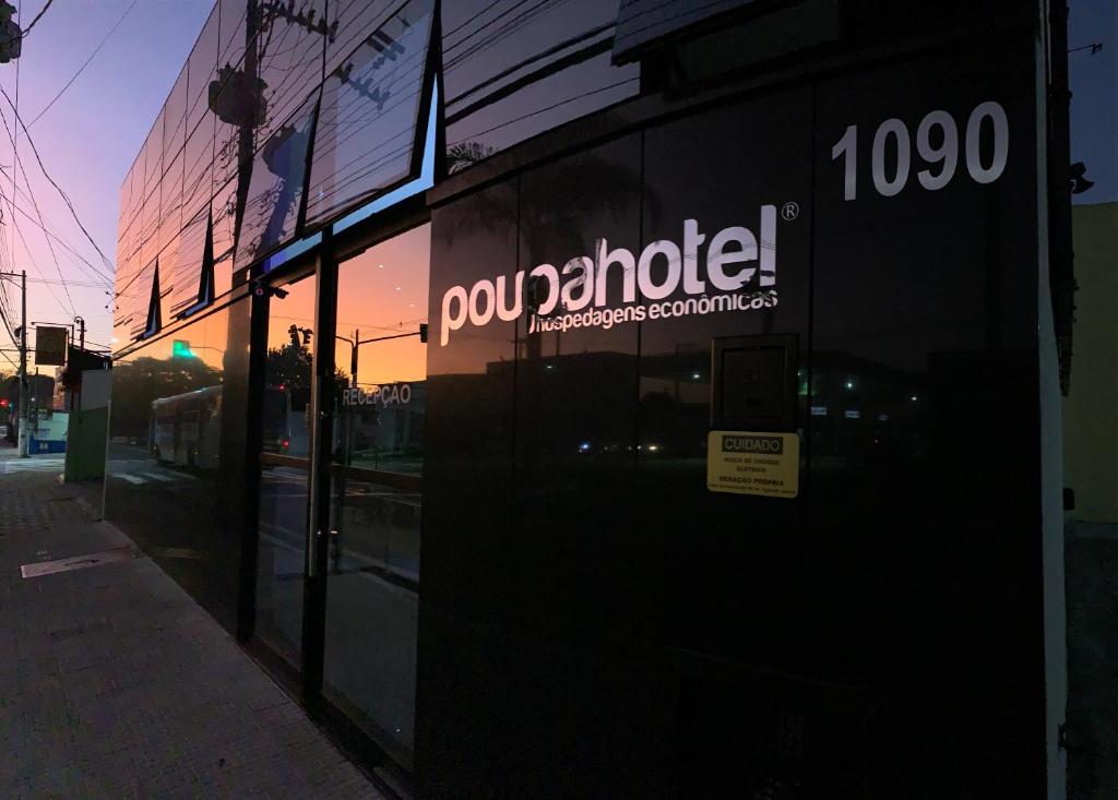 a store with a sign on the side of a building at Poupahotel in Taubaté