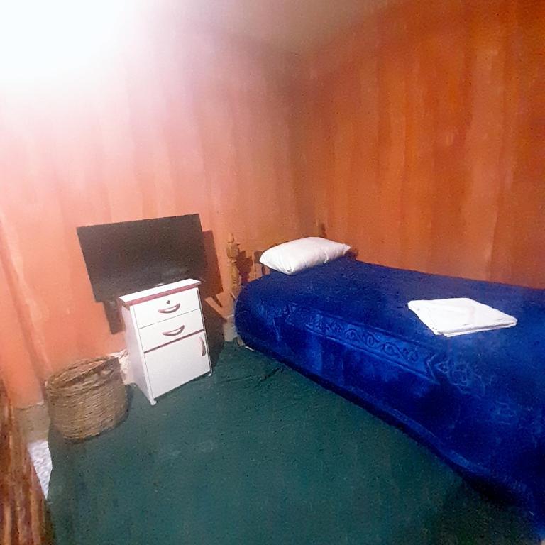 1 dormitorio con 1 cama y mesita de noche con manta azul en hostal las americas, 
