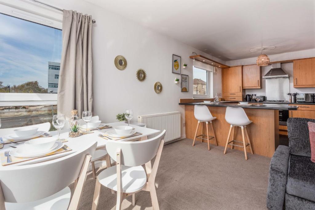a dining room with a table and chairs and a kitchen at Walker Suite No52 - Donnini Apartments in Kilmarnock