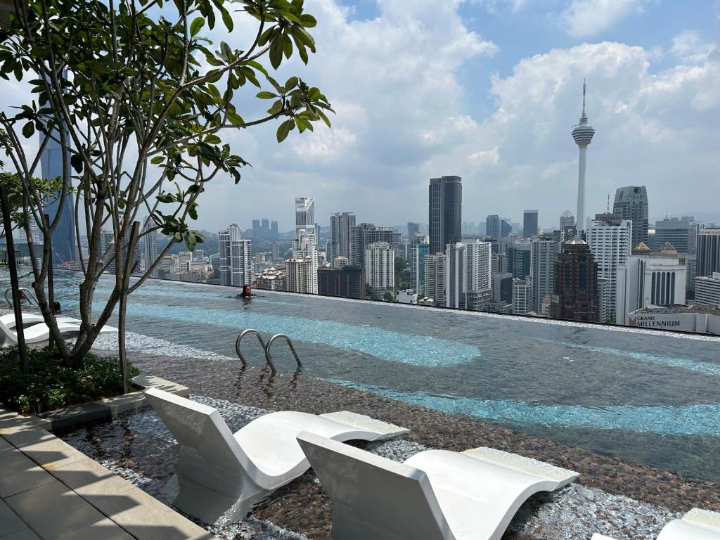 a swimming pool with chairs and a city skyline at Axon Residence at Pavilion KLCC KL Tower view by KIMIRO in Kuala Lumpur