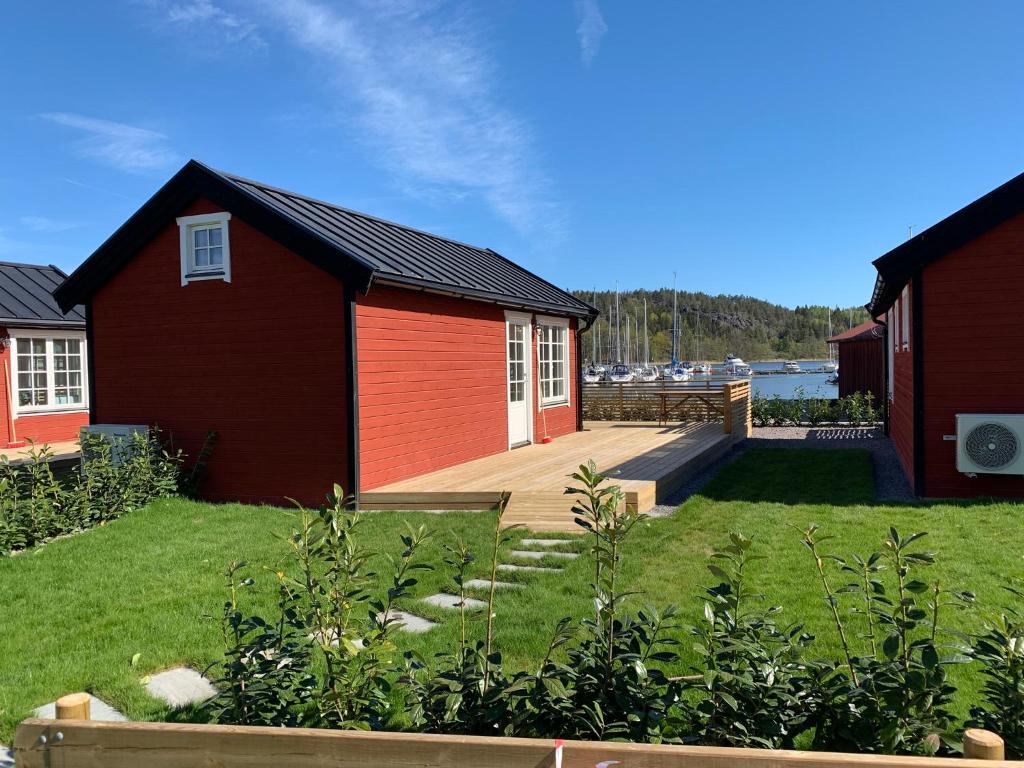 una casa roja con terraza y patio en Lyxiga stugor med sjöutsikt, en Söderköping