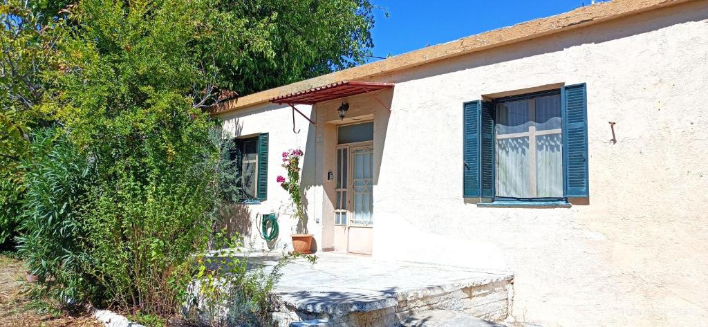 a white house with blue shutters on it at To Spitaki 