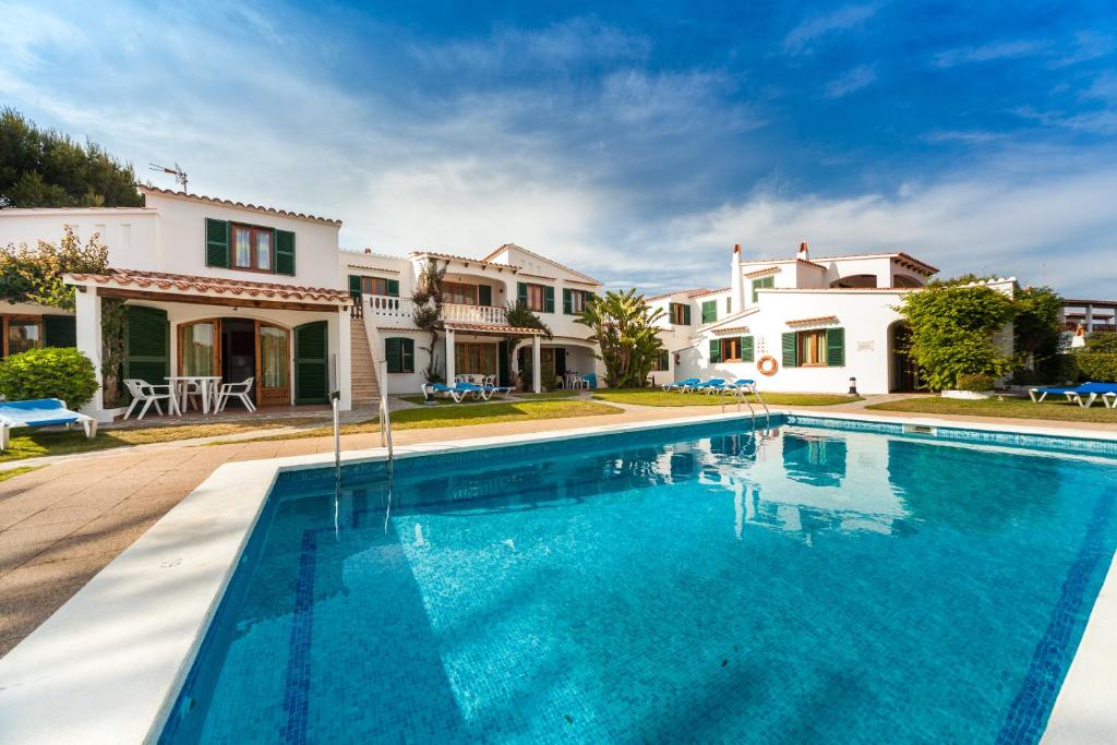 a large swimming pool in front of a house at Apartamentos Arenal Playa in Punta Grossa